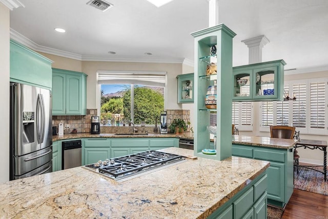 kitchen with stainless steel appliances, ornamental molding, sink, and green cabinets