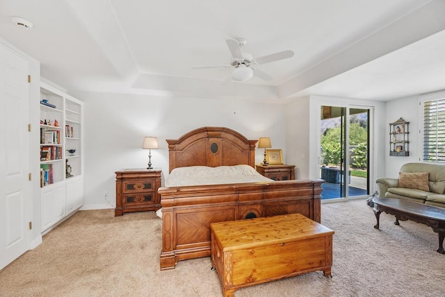 bedroom featuring light carpet, access to exterior, ceiling fan, and a tray ceiling