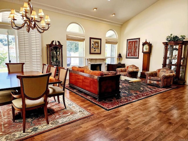 interior space with crown molding, a premium fireplace, high vaulted ceiling, a notable chandelier, and wood-type flooring