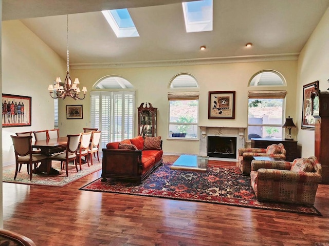 living room with crown molding, hardwood / wood-style floors, a notable chandelier, and a fireplace