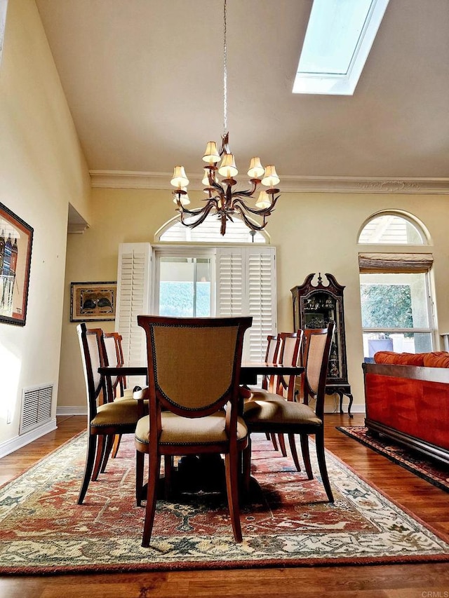 dining space with lofted ceiling with skylight, wood-type flooring, a wealth of natural light, and a chandelier