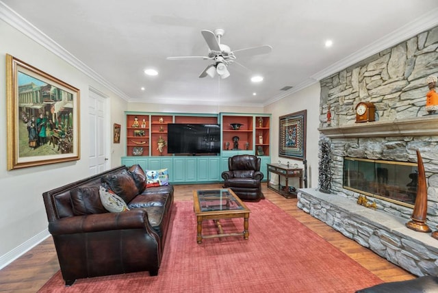 living room with ceiling fan, ornamental molding, a fireplace, and wood-type flooring