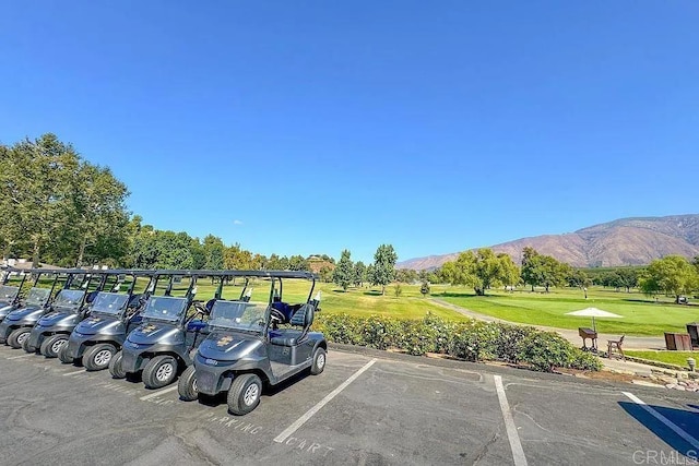 view of car parking with a carport, a mountain view, and a lawn