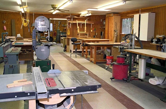 misc room featuring wood walls, ceiling fan, and a workshop area