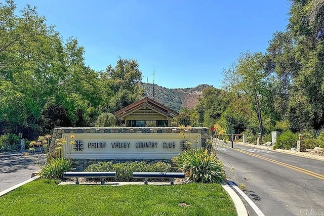 community / neighborhood sign with a mountain view and a lawn