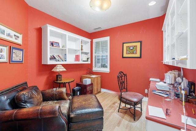 office area with built in shelves and light hardwood / wood-style flooring