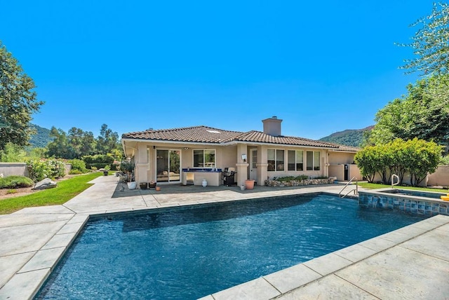 back of property featuring a swimming pool with hot tub and a patio area