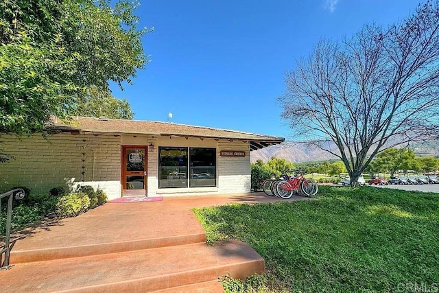 doorway to property featuring a mountain view and a yard