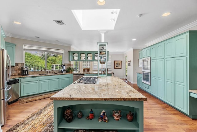 kitchen with ornamental molding, appliances with stainless steel finishes, a center island, and sink