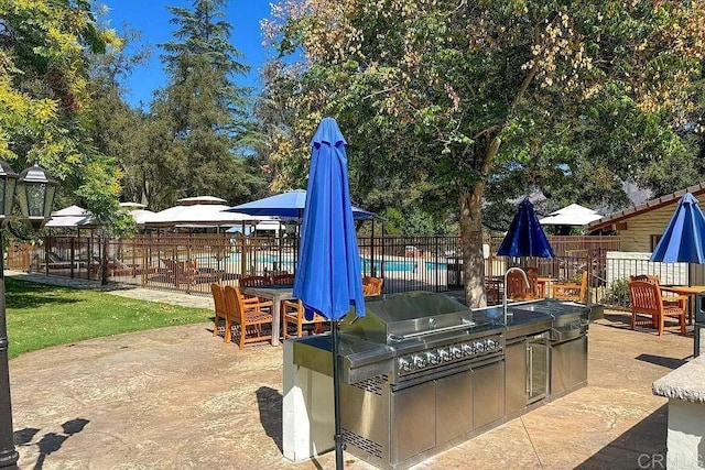 view of patio / terrace featuring a fenced in pool, an outdoor kitchen, and area for grilling