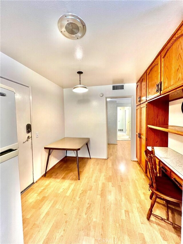 kitchen with pendant lighting, light hardwood / wood-style flooring, and fridge