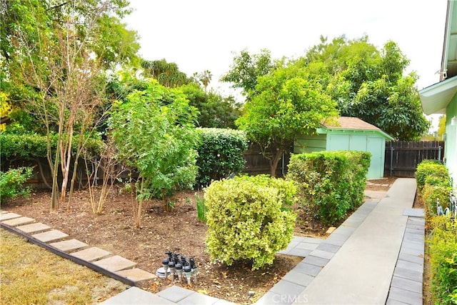 view of yard featuring a fenced backyard, a storage unit, and an outdoor structure