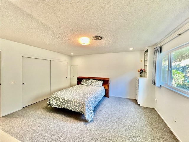 carpeted bedroom featuring a textured ceiling and a closet