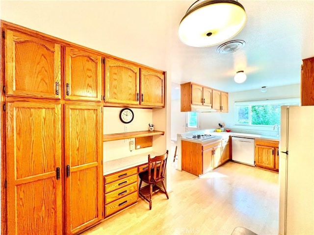 kitchen featuring sink, white appliances, built in desk, and light wood-type flooring