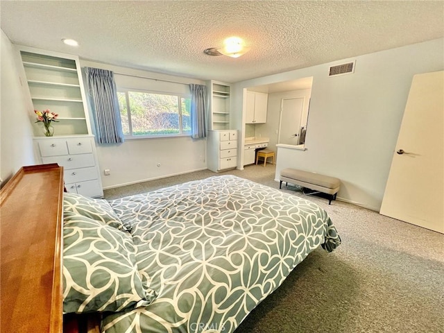 carpeted bedroom featuring baseboards, visible vents, and a textured ceiling