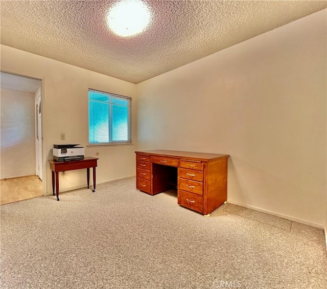 office space with light carpet, a textured ceiling, and baseboards