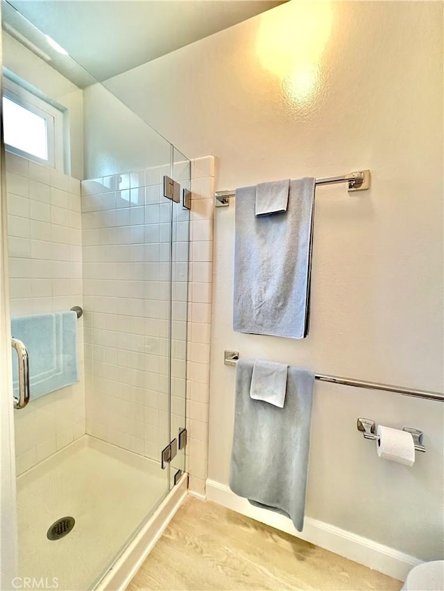 bathroom with a shower with door and wood-type flooring