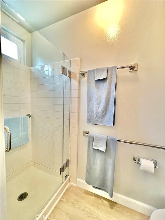 full bath with a shower stall, baseboards, and wood finished floors