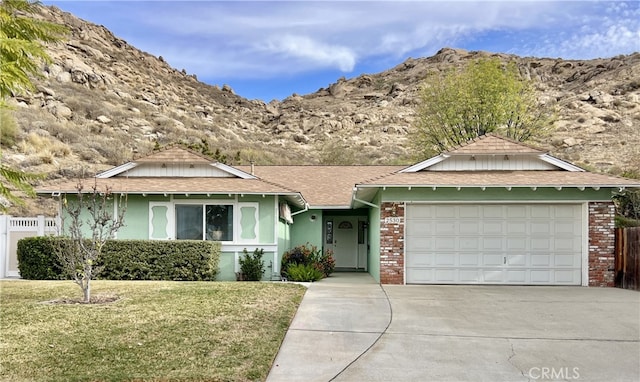 ranch-style home featuring brick siding, concrete driveway, an attached garage, a mountain view, and a front yard