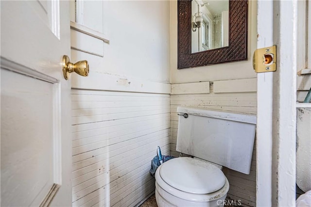 bathroom featuring wooden walls and toilet