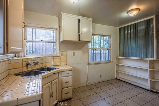 kitchen featuring tasteful backsplash, sink, light tile patterned floors, and tile countertops