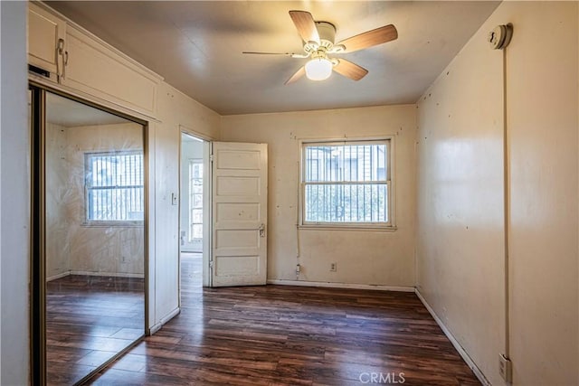 unfurnished bedroom with ceiling fan, dark hardwood / wood-style flooring, and a closet