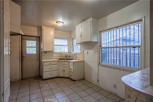 kitchen with white cabinetry, sink, a wealth of natural light, and decorative backsplash