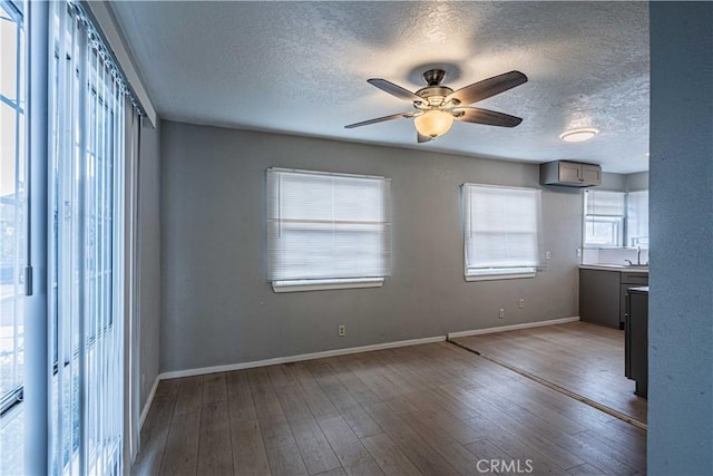 unfurnished room featuring hardwood / wood-style flooring, ceiling fan, sink, and a textured ceiling