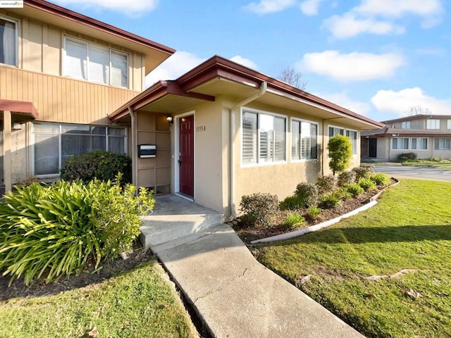 view of exterior entry featuring a lawn