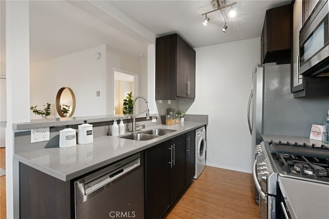 kitchen featuring dark brown cabinetry, sink, light wood-type flooring, stainless steel appliances, and washer / clothes dryer