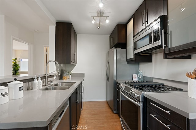 kitchen with dark brown cabinetry, appliances with stainless steel finishes, light hardwood / wood-style floors, and sink