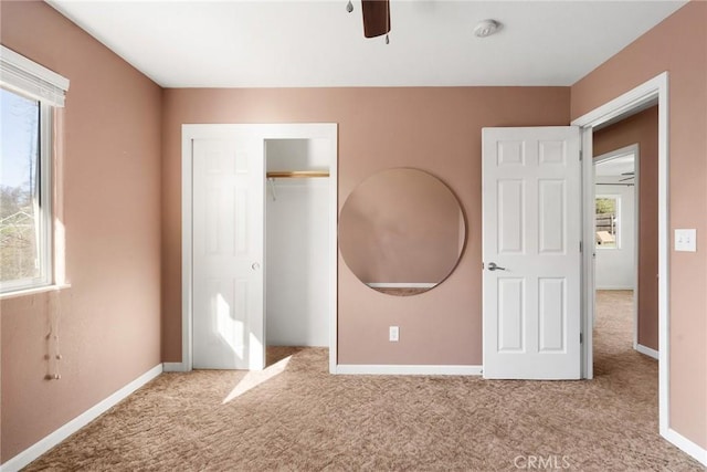 unfurnished bedroom featuring light carpet, ceiling fan, and a closet