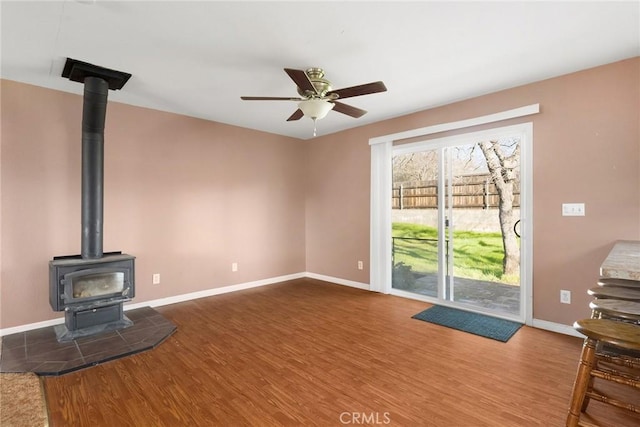 unfurnished living room featuring hardwood / wood-style flooring, a wood stove, and ceiling fan