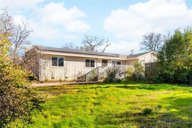 back of property featuring a lawn and solar panels