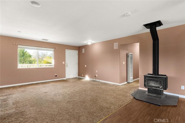 unfurnished living room with carpet floors and a wood stove