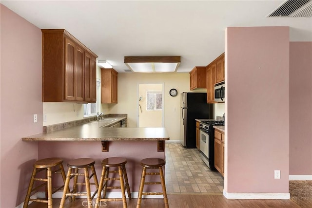 kitchen with sink, a breakfast bar area, stainless steel appliances, and kitchen peninsula