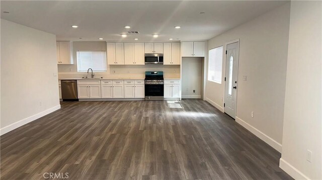 kitchen with stainless steel appliances, white cabinetry, sink, and dark wood-type flooring