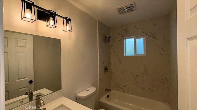 full bathroom with tiled shower / bath, vanity, and toilet