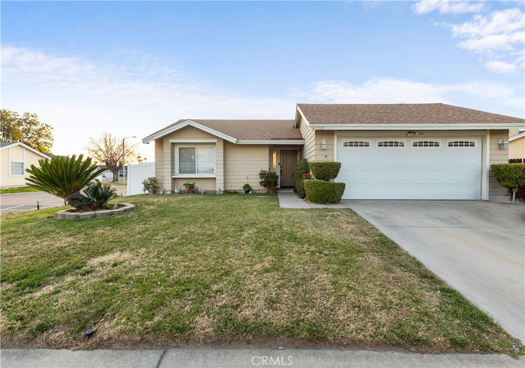 single story home with a garage and a front lawn