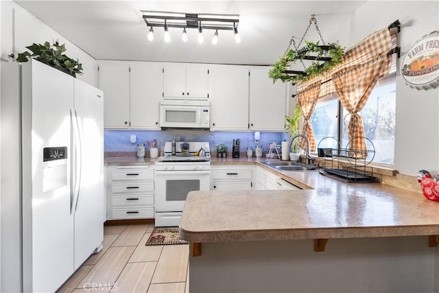 kitchen featuring white appliances, kitchen peninsula, sink, and white cabinets