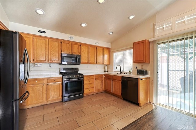 kitchen featuring lofted ceiling, sink, and black appliances