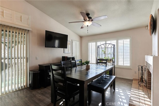 dining area with a fireplace, vaulted ceiling, dark hardwood / wood-style floors, and ceiling fan