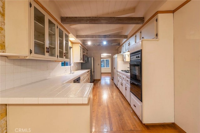 kitchen featuring stainless steel gas cooktop, sink, tile countertops, light hardwood / wood-style flooring, and decorative backsplash