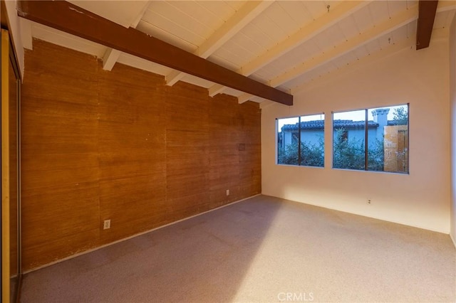 carpeted spare room with vaulted ceiling with beams and wooden walls