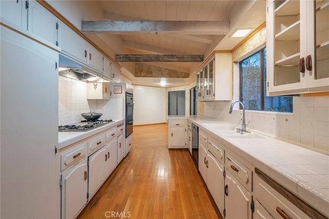 kitchen with white cabinetry, sink, tile countertops, and lofted ceiling with beams