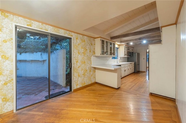 kitchen with sink, stainless steel fridge, vaulted ceiling with beams, white cabinets, and light wood-type flooring