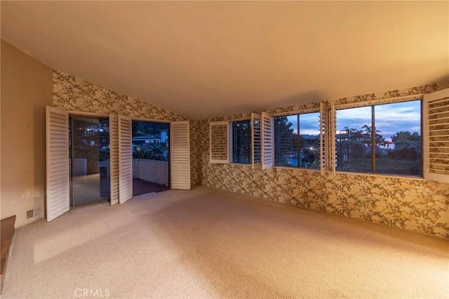 unfurnished living room with vaulted ceiling and carpet flooring