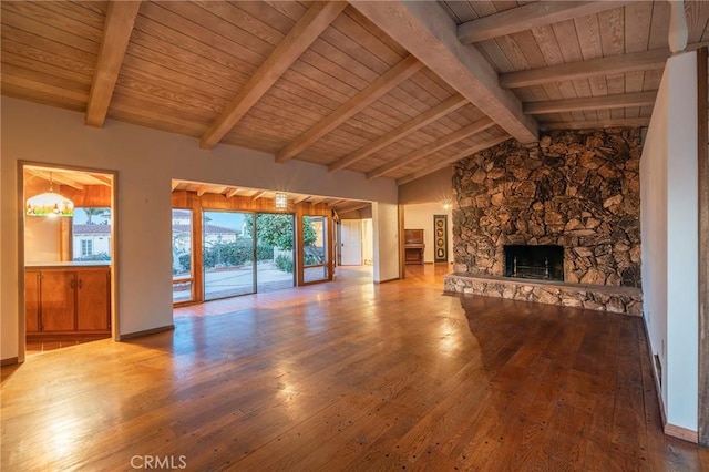 unfurnished living room with hardwood / wood-style flooring, wooden ceiling, a stone fireplace, and vaulted ceiling with beams