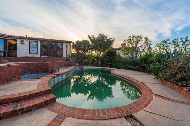 pool at dusk with a patio area