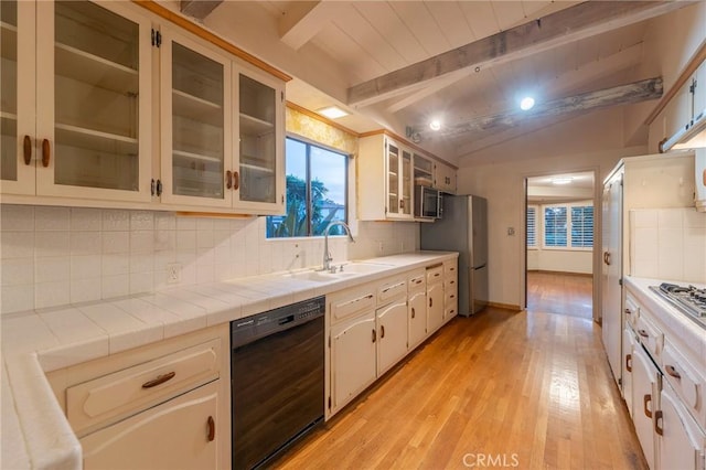 kitchen featuring appliances with stainless steel finishes, tile countertops, vaulted ceiling with beams, sink, and backsplash